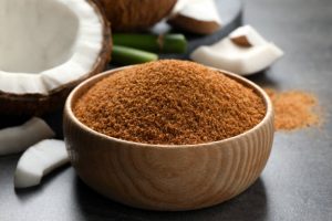 Natural coconut sugar in wooden bowl on grey table